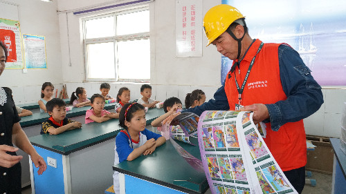 該公司黨員服務隊隊員李萬福在為孩子們發放電力安全三字經